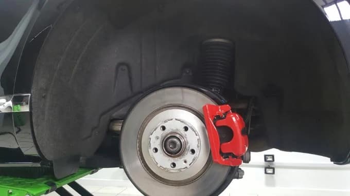 Red brake caliper and wheel arch detail on vehicle at Ceramic Pro North West, Bolton, Greater Manchester